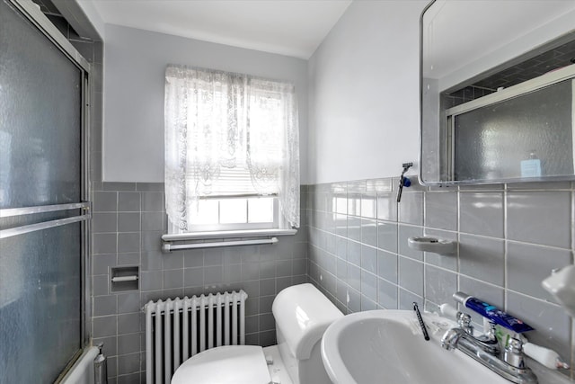 bathroom featuring radiator, tile walls, a sink, an enclosed shower, and plenty of natural light