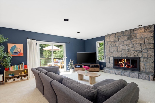 carpeted living area featuring healthy amount of natural light and a stone fireplace