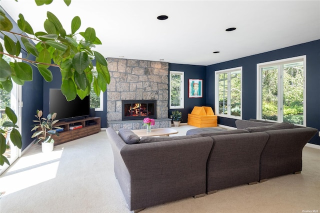 carpeted living area with a stone fireplace