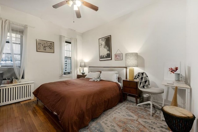 bedroom with radiator, multiple windows, ceiling fan, and hardwood / wood-style flooring