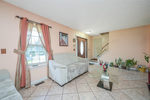 living room with stairs, light tile patterned flooring, baseboards, and visible vents