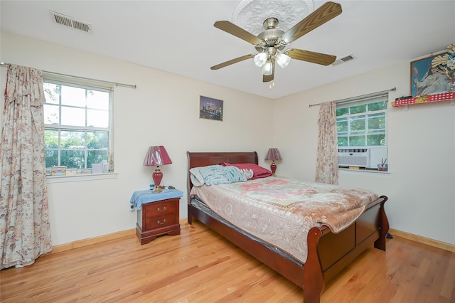 bedroom with multiple windows, visible vents, and wood finished floors