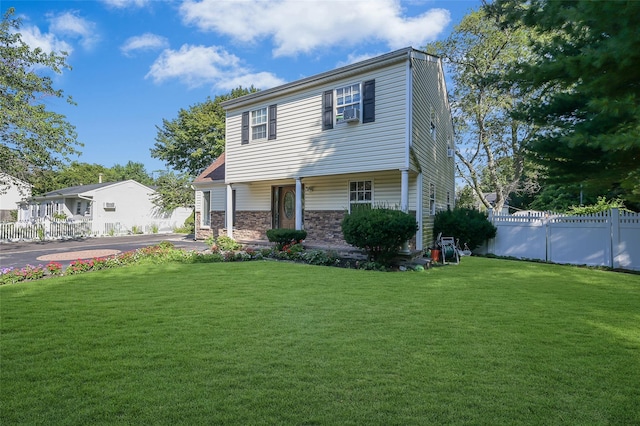 view of front of house with a front yard, aphalt driveway, stone siding, and fence