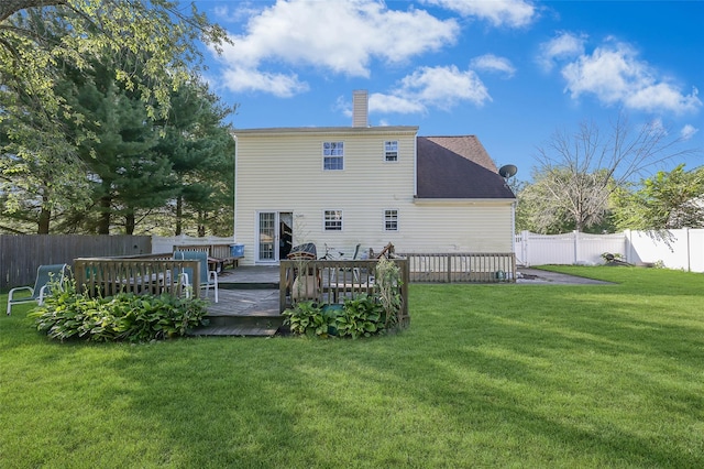 rear view of house with a yard, a chimney, a deck, and a fenced backyard