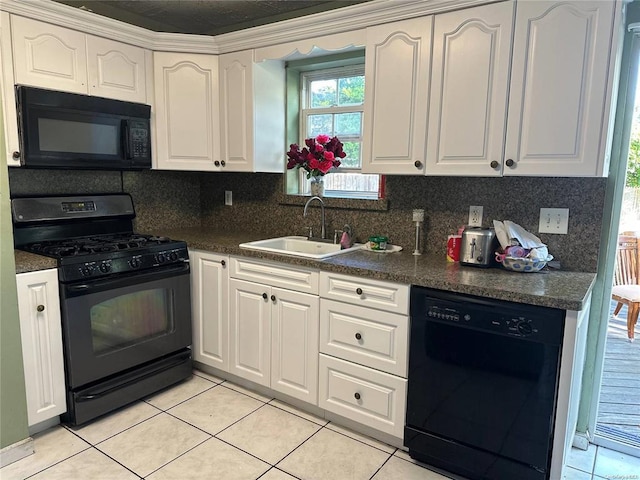 kitchen with a sink, light tile patterned flooring, black appliances, white cabinetry, and dark countertops