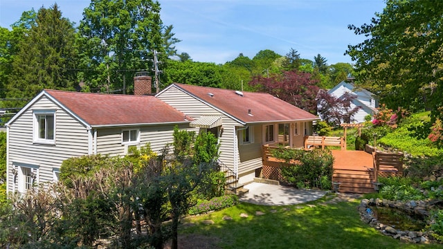 202 W Main St, Mount Kisco, NY 10549 - back of property with a chimney, a wooden deck, a lawn, a shingled roof, and a patio