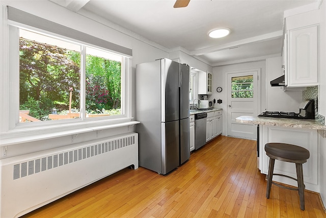 202 W Main St, Mount Kisco, NY 10549 - kitchen featuring radiator heating unit, stainless steel appliances, extractor fan, white cabinetry, and light wood finished floors