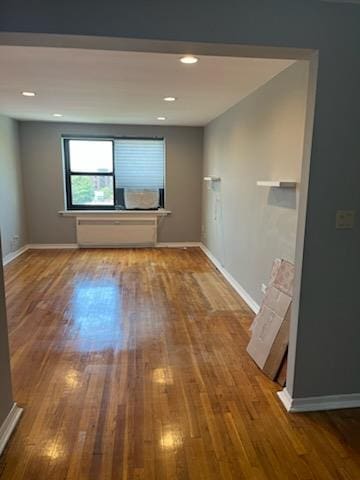 spare room with baseboards and wood finished floors