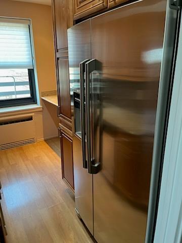 kitchen featuring light countertops, light wood-type flooring, high end fridge, and brown cabinetry