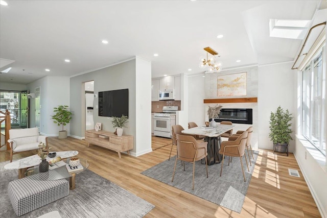 1601 Pondcrest Ln, White Plains, NY 10607 - living area featuring light wood finished floors, a chandelier, a glass covered fireplace, recessed lighting, and a skylight