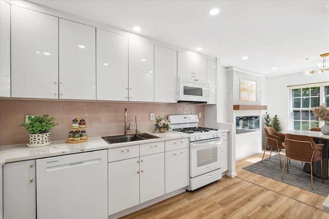 1601 Pondcrest Ln, White Plains, NY 10607 - kitchen featuring white appliances, a sink, white cabinetry, light wood-type flooring, and decorative backsplash