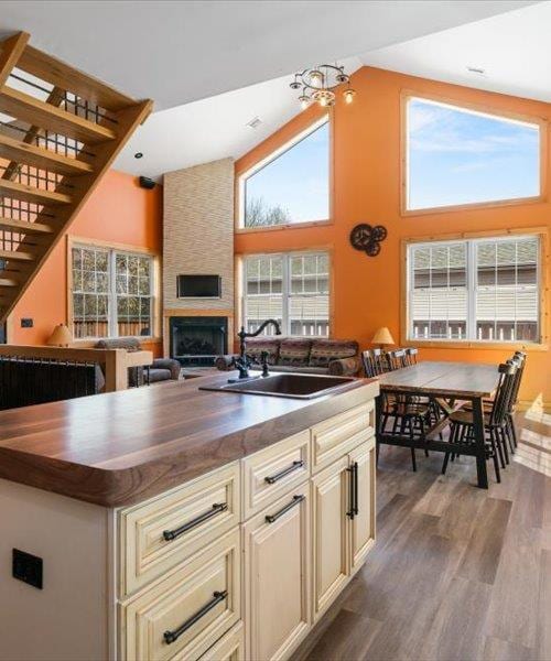 kitchen featuring a sink, butcher block counters, high vaulted ceiling, and cream cabinets