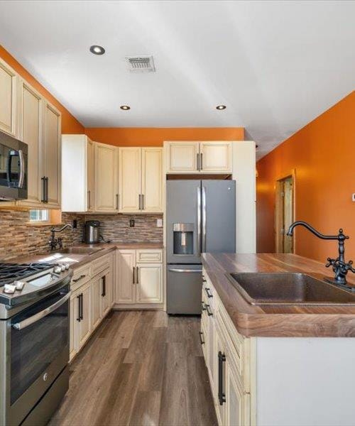 kitchen featuring a sink, appliances with stainless steel finishes, dark wood-type flooring, tasteful backsplash, and recessed lighting