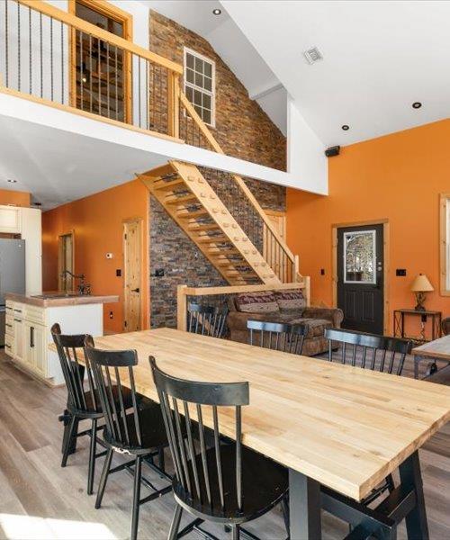 dining room featuring high vaulted ceiling, wood finished floors, and stairs