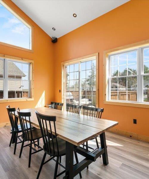 dining space featuring wood finished floors, baseboards, high vaulted ceiling, and recessed lighting