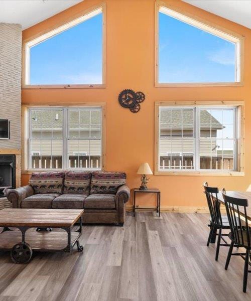 living room with a towering ceiling, wood finished floors, healthy amount of natural light, and a fireplace