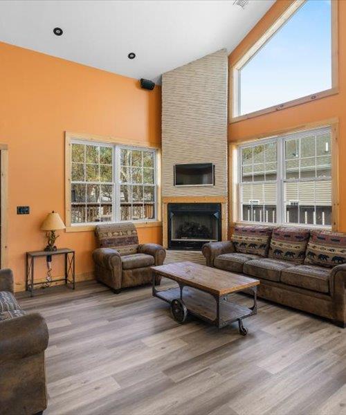living area with a high ceiling, wood finished floors, and a large fireplace