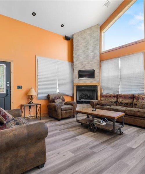 living room featuring high vaulted ceiling, wood finished floors, and a fireplace