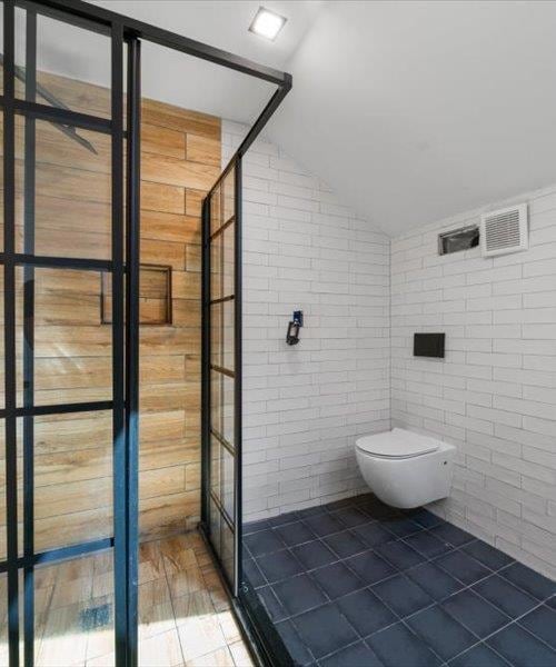 full bath with tile patterned flooring, tile walls, a shower stall, vaulted ceiling, and toilet