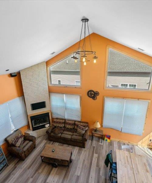 living room with wood finished floors, lofted ceiling, a large fireplace, and healthy amount of natural light