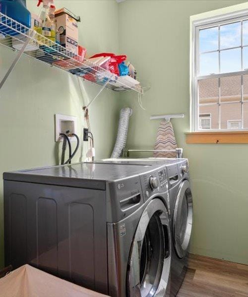clothes washing area with washing machine and dryer and wood finished floors