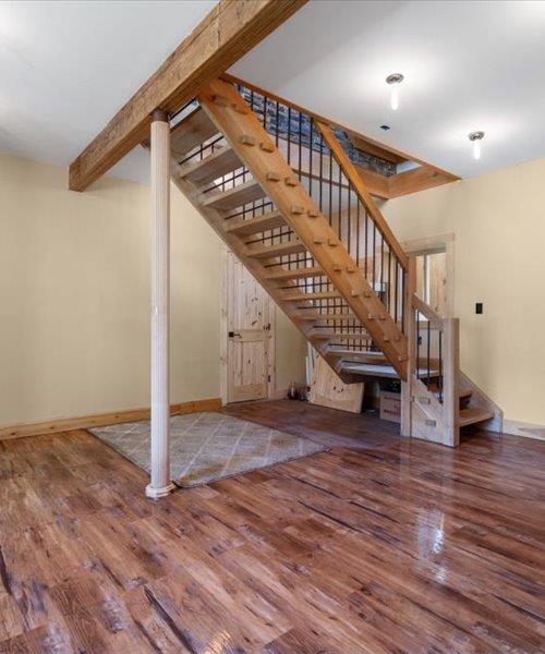 unfurnished living room featuring wood finished floors, stairway, and baseboards