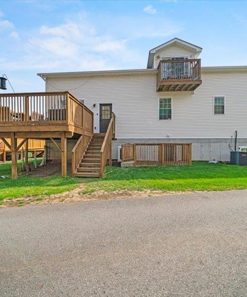 back of house featuring stairway, a deck, a yard, and central AC unit