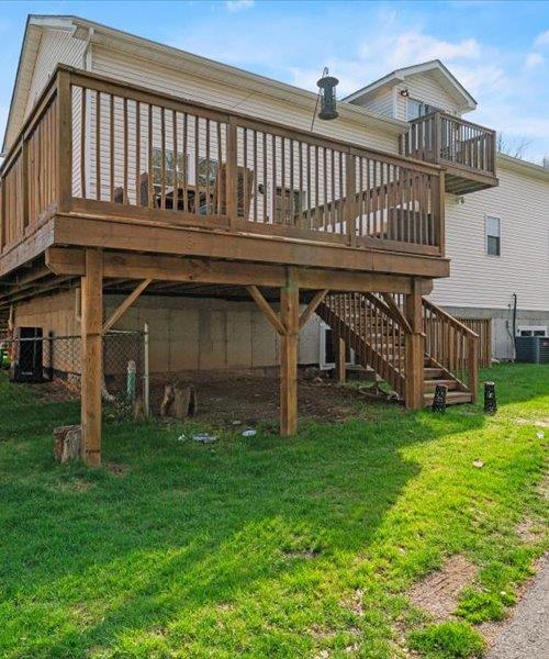 back of property with a yard, a deck, and central AC