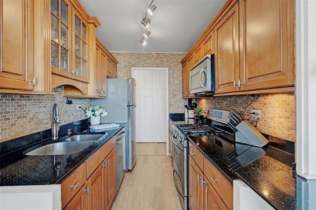 kitchen featuring a sink, brown cabinetry, dark stone countertops, and appliances with stainless steel finishes