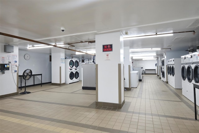 common laundry area with washer and dryer, stacked washer / drying machine, visible vents, tile patterned flooring, and baseboards