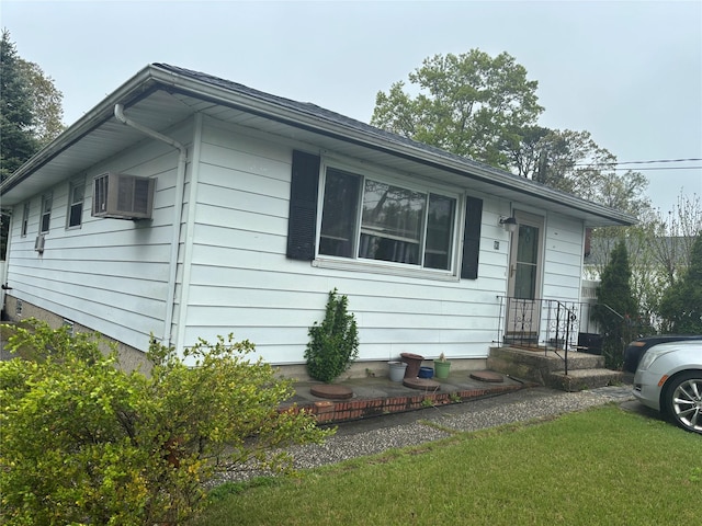 ranch-style house with a front lawn and a wall unit AC