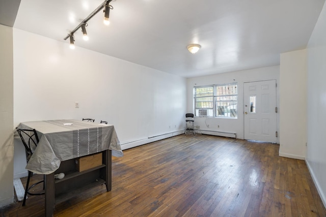 unfurnished dining area with rail lighting, baseboards, a baseboard heating unit, and hardwood / wood-style flooring