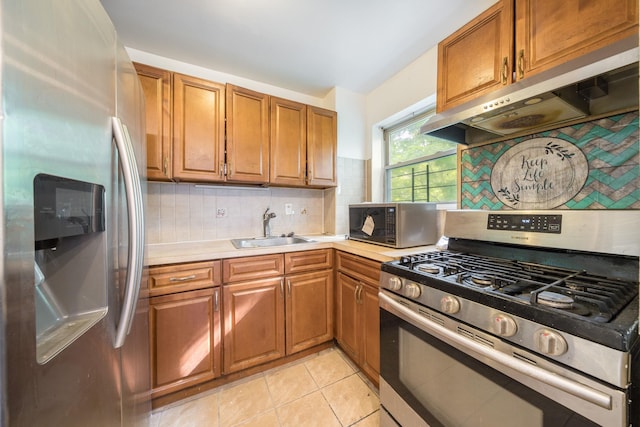 kitchen with a sink, stainless steel appliances, brown cabinets, under cabinet range hood, and light countertops