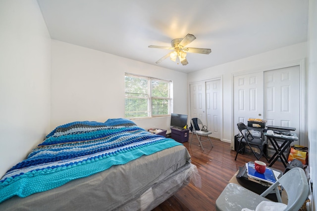bedroom with ceiling fan, wood finished floors, and multiple closets