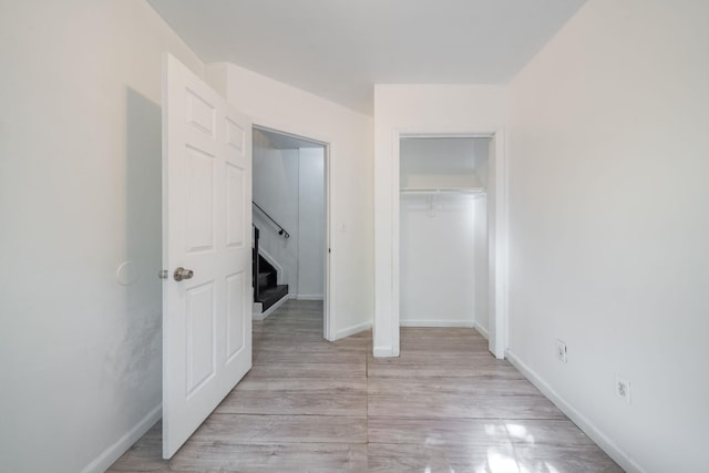unfurnished bedroom with light wood finished floors, a closet, and baseboards