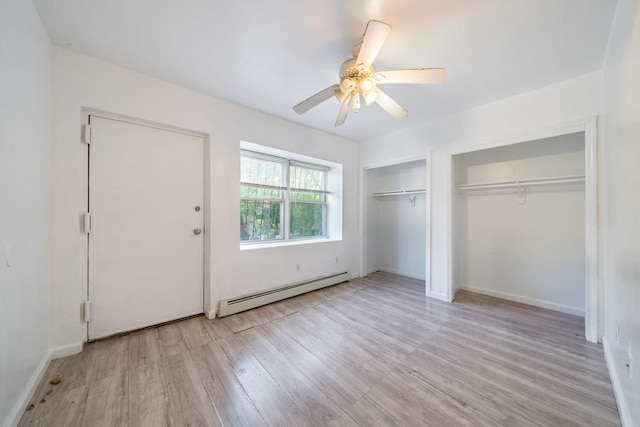 unfurnished bedroom with wood finished floors, a baseboard radiator, ceiling fan, two closets, and baseboards