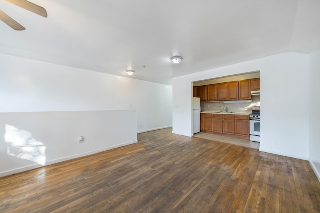 unfurnished living room with baseboards, a ceiling fan, hardwood / wood-style floors, and a sink