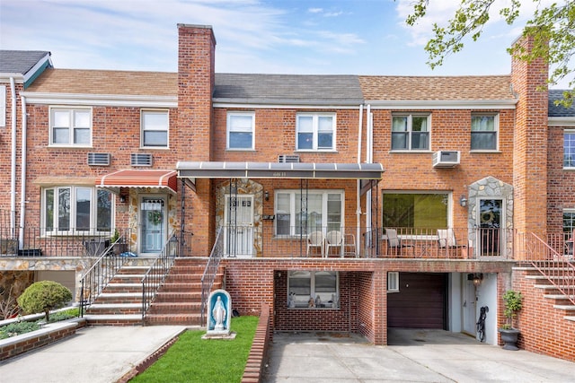 view of front of house featuring brick siding, a wall mounted AC, and a chimney
