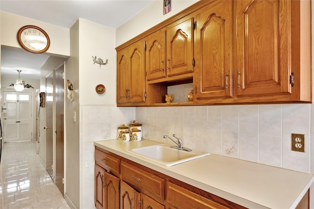 kitchen with a sink, brown cabinetry, open shelves, light countertops, and light tile patterned floors