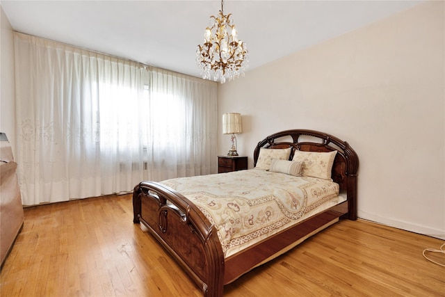 bedroom with wood finished floors and a notable chandelier