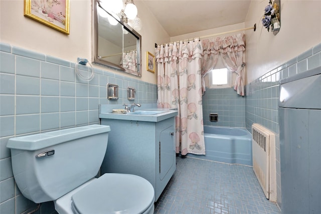 bathroom featuring toilet, shower / bath combo with shower curtain, tile walls, vanity, and radiator heating unit