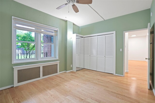 unfurnished bedroom featuring radiator heating unit, light wood-style flooring, and baseboards