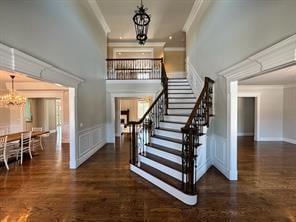 2 Enclave Ct, Dix Hills, NY 11746 - stairway featuring a chandelier, crown molding, a towering ceiling, a decorative wall, and wood finished floors