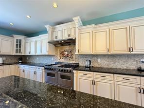 2 Enclave Ct, Dix Hills, NY 11746 - kitchen featuring range with two ovens, under cabinet range hood, tasteful backsplash, glass insert cabinets, and recessed lighting