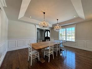 2 Enclave Ct, Dix Hills, NY 11746 - dining space featuring a tray ceiling, a chandelier, a decorative wall, wood finished floors, and wainscoting