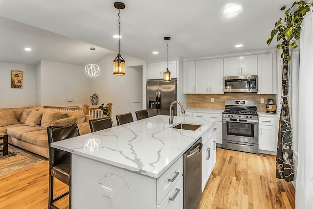 1 Valley Forge Dr, Wheatley Heights, NY 11798 - kitchen featuring stainless steel appliances, a sink, a breakfast bar area, light wood-type flooring, and white cabinets