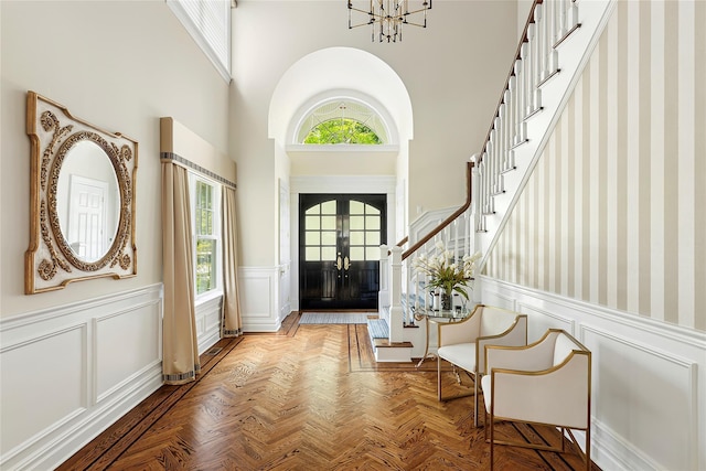 1608 Stewart Ln, Laurel Hollow, NY 11791 - foyer with stairs, a wainscoted wall, a high ceiling, a decorative wall, and a chandelier