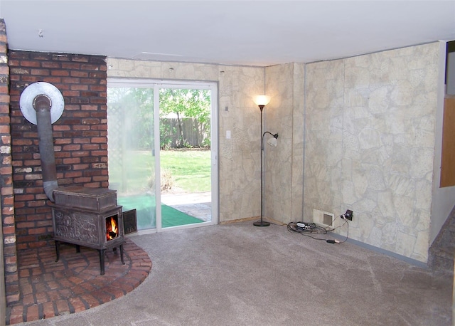 unfurnished living room featuring a wood stove and carpet