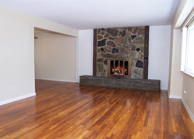 unfurnished living room with a fireplace, baseboards, and wood finished floors