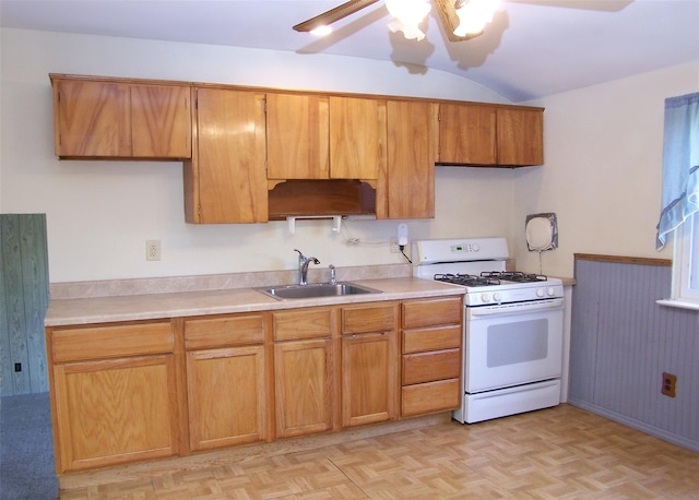 kitchen featuring a sink, brown cabinetry, white gas range, ceiling fan, and light countertops